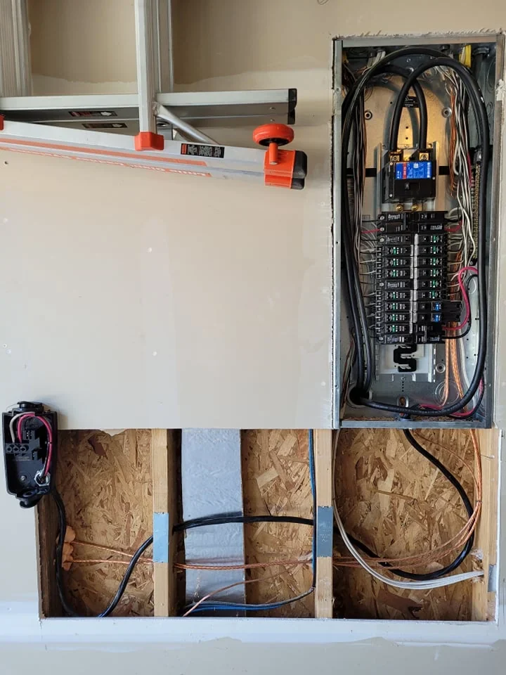 Open residential electrical panel with breakers and wiring exposed during installation.