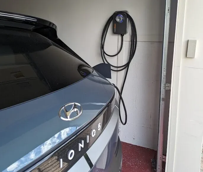 Wall-mounted home EV charger beside a Hyundai Ioniq 5 in a garage.