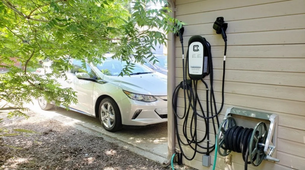 Dual-connector home EV charging station mounted beside a parked electric car.